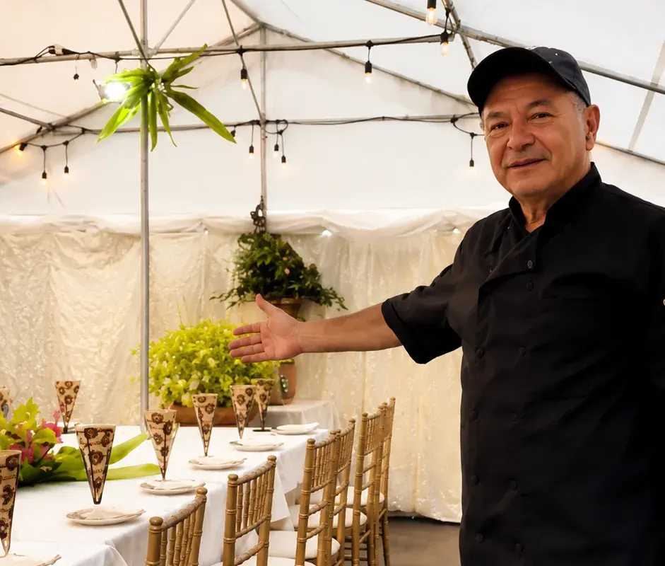 Chef Tony welcoming guests to the private garden, set with gold chairs and long tables